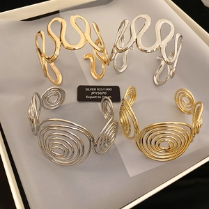 Detailed view of wave and spiral 925 silver bangles in gold and silver finishes