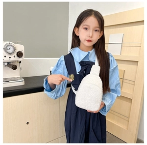 White plush fleece crossbody bag for kids shown being worn in a cozy indoor setting