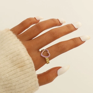 Detail of a gold chain link ring featuring a purple enamel heart charm on a finger