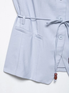 Detail of light blue vest featuring beaded drawstring waist and cotton linen texture