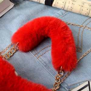 Macro shot of fluffy red faux fur bag handle and elegant gold metal chain strap detail