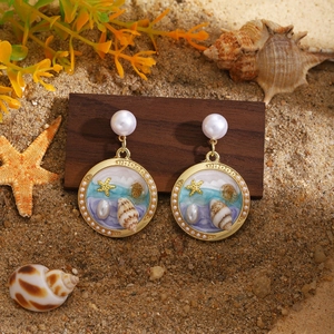 Dettaglio orecchini con perle stelle marine su supporto in legno stile spiaggia