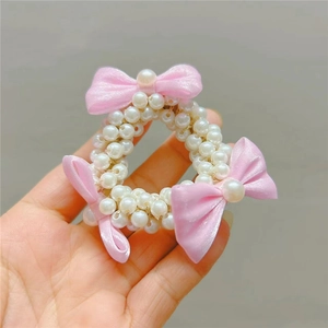 Handheld view of pearl beaded hair ring with three pink ribbon bows for little girls
