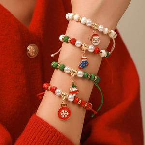 Set de bracelets de Noël avec flocons et père Noël portés sur un pull en maille rouge