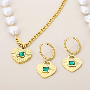 Detail of gold heart pendant with green gemstone on pearl and curb chain necklace set