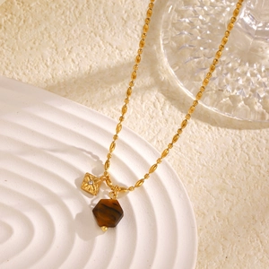 Chic gold necklace featuring tiger eye stone and crystal square pendant on white ceramic tray