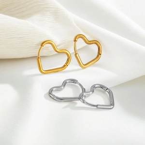 Detail of heart-shaped hoop earrings in gold and silver finish on soft silk fabric