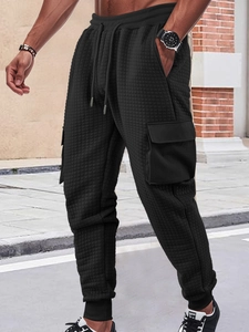 Detail of black textured cargo joggers featuring side flap pockets and drawstring waist