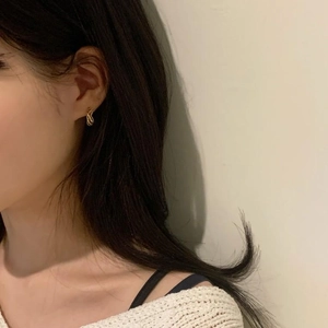 Close-up of a minimalist gold twisted rope hoop earring worn by a model in profile