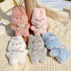 Présentation de pendentifs lapin en peluche en cinq couleurs sur tissu texturé beige