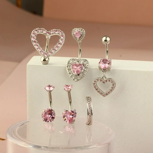 Detail shot of silver navel rings with pink heart zircons on white geometric steps
