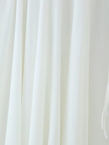 Détail de la texture du tissu blanc montrant des volants délicats et le drapé de la robe