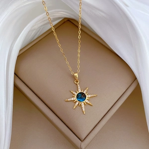 Star-shaped gold necklace with a blue gemstone center inside a luxury jewelry box