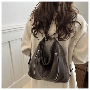 Détail des fermetures éclair argentées et texture en cuir souple du sac Hobo marron