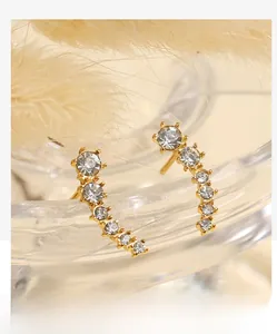 Macro shot of curved gold ear crawlers with gradient white zircons on glass rim