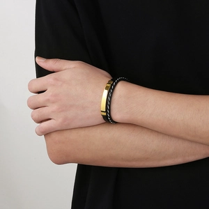 Men's black braided leather bracelet with a polished gold stainless steel curved plate
