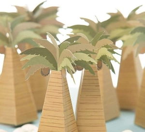 Macro view of coconut tree shaped paper candy gift boxes on a blue beach themed background
