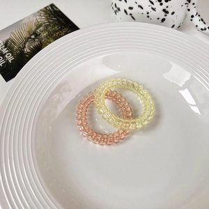 Detail of pink and yellow spiral hair ties in a decorative ceramic plate