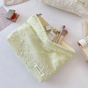 Detailed embroidery on light green lace makeup bag with 3D floral patterns and metal zipper