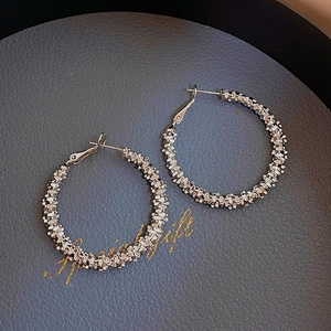Macro shot of silver textured hoop earrings with sparkling metallic grain finish