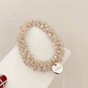 Close-up of crystal faceted beads hair tie with silver metal tag engraved with LUNA