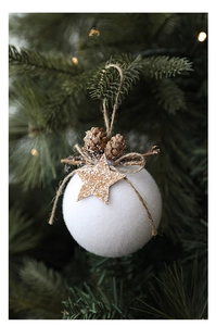 White flocked Christmas ball with pine cone and wooden star detail on a green tree