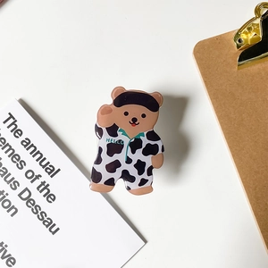 Close-up of cute cartoon bear phone socket in cow print pajamas on white desk