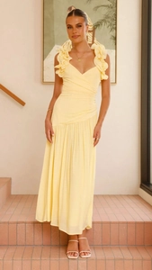Détail d'une robe jaune pâle à col en V avec des bretelles à volants et une taille haute