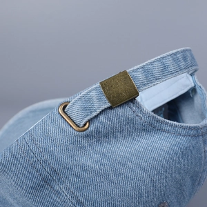 Detail of adjustable bronze metal buckle on vintage blue denim baseball cap back
