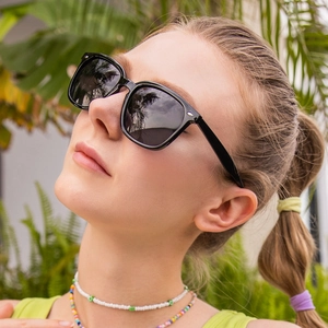 Close-up of black oversized square sunglasses with silver rivet accents on a model