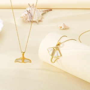 Detail von goldenen Halsketten mit Walflossen- und Rochenanhängern im Meeresstil