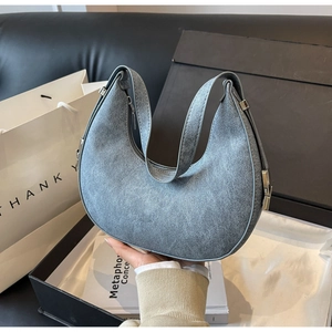Close-up of minimalist grey-blue crescent moon underarm bag with zipper and silver hardware
