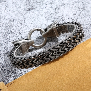 Detailed macro shot of vintage double wolf head metal clasp on a braided men's chain bracelet