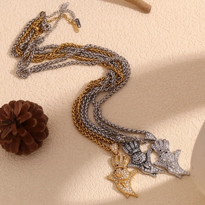 Detailed view of three iced-out lobster pendants in gold silver and grey on rope chains