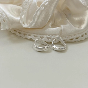 Détail des boucles d'oreilles irrégulières en argent 925 sur tissu en soie et dentelle