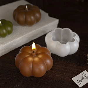 Macro view of white pumpkin silicone mold and finished candles on a wooden table