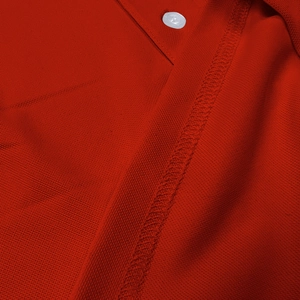 Macro shot of red piqué cotton fabric showing breathable mesh texture and white button