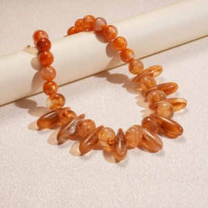Detailed close-up of acrylic beads and amber drop charms on a minimalist necklace