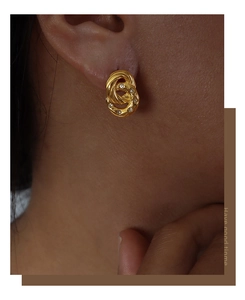 Close-up of interlocking gold-plated double rings earrings set with zircon stones on model