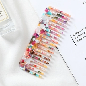 Close-up of wide-tooth marble acetate hair comb on aesthetic lifestyle magazine background