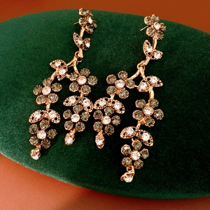 Macro detail of vintage gold floral tassel earrings with sparkling rhinestones on velvet