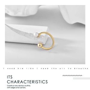 Detailed shot of open golden ring featuring a white pearl and metallic ball minimalist design