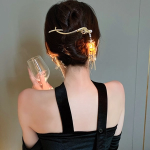 Detail showing glowing lantern charm and pearl tassels on a Chinese style hair stick