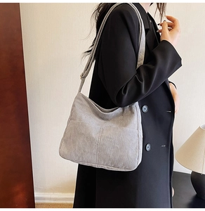 Detail of grey corduroy shoulder bag showing texture and crossbody wear on model
