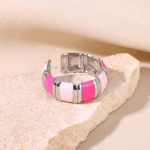 Macro shot of 18K gold plated enamel ring in pink and white on a beige stone base