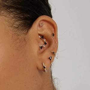 Detailed view of a gold-plated ear cuff set with black triangle stones and white crystals