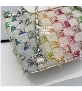 Close-up of colorful tweed bucket bag with fringe edges and metal chain strap details