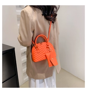 Mannequin portant un sac en cuir matelassé orange vif avec une mini pochette assortie