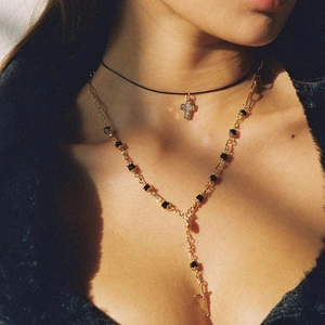Close-up of double-layer titanium steel cross necklace with black beads and gold finish