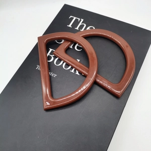 Detail of pair of brown D-shaped resin handles for DIY knitted handbags on a book